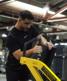 Hombre entrenando con máquina de empuje para cuádriceps en gimnasio.